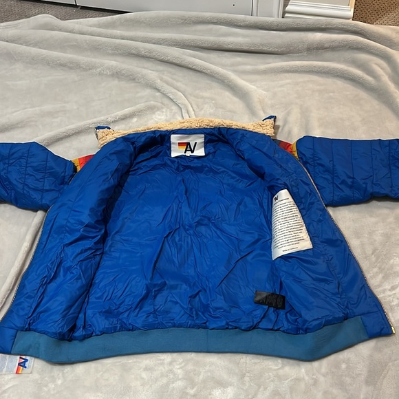 Jacket is Blue with a rainbow going across the chest. It is a Children’s size L. - Picture 2 of 4